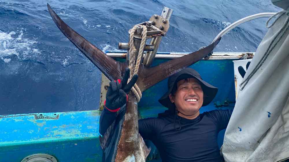 カジキを釣り上げピースサインの男性