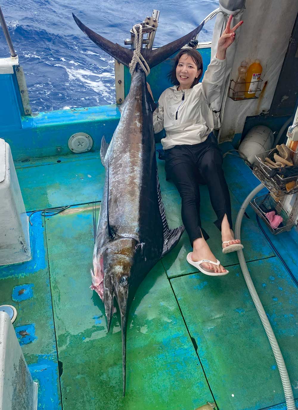 自ら釣り上げたカジキとピースサインの女性