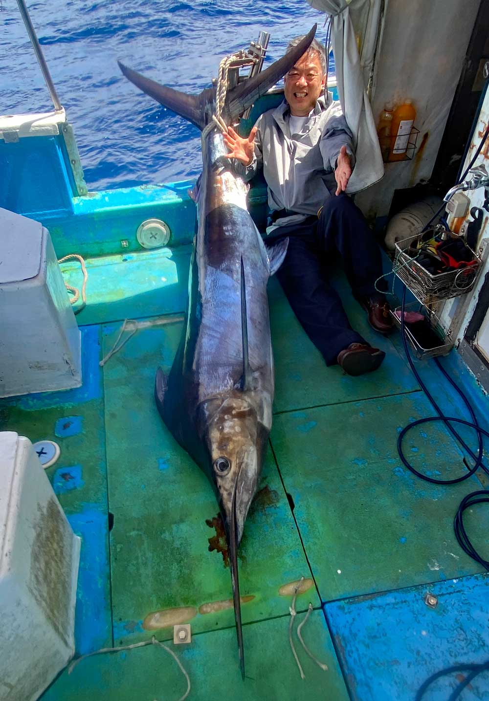 クロカジキと釣り上げた男性