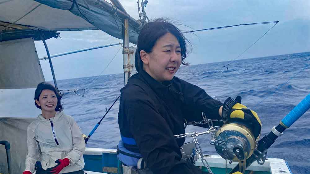 沖縄カジキを釣っている女性と後ろで見守る女性