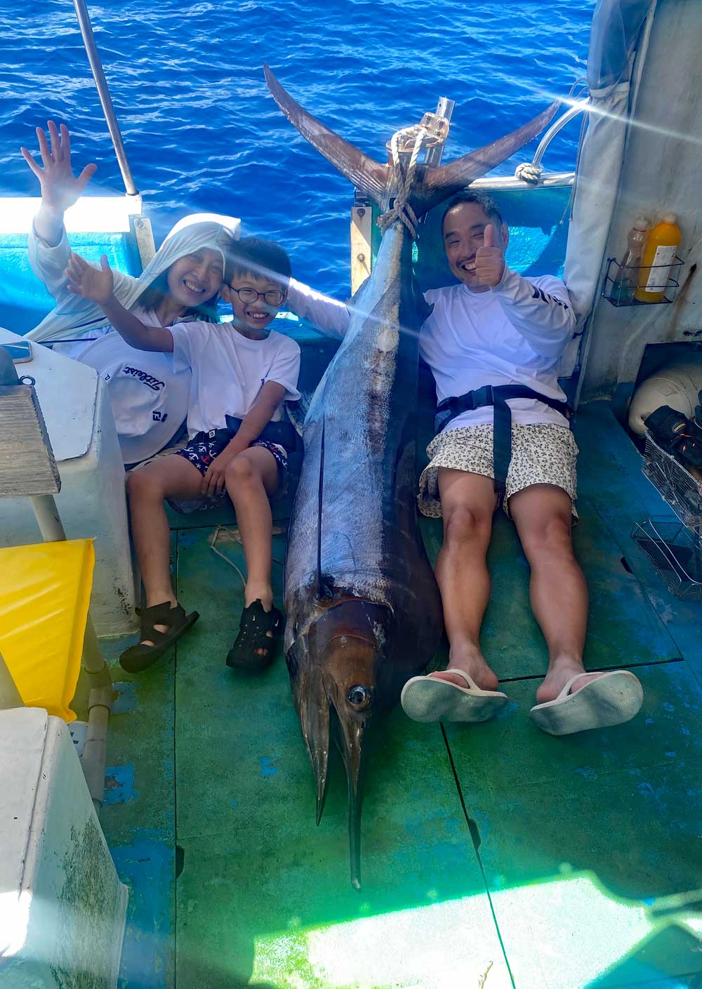 カジキを釣り上げ喜ぶ親子3人