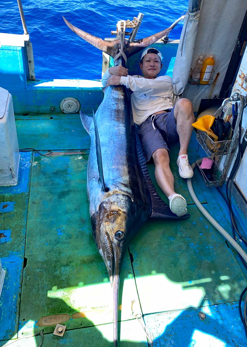 自ら釣り上げたカジキを両手でかかえている男性
