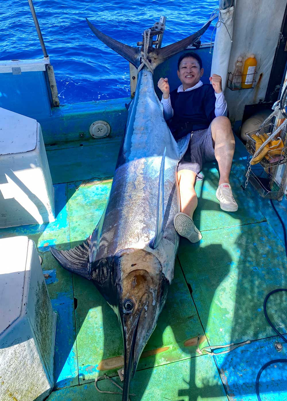 沖縄のトローリングで釣り上げた120kgのカジキとガッツポーズの男