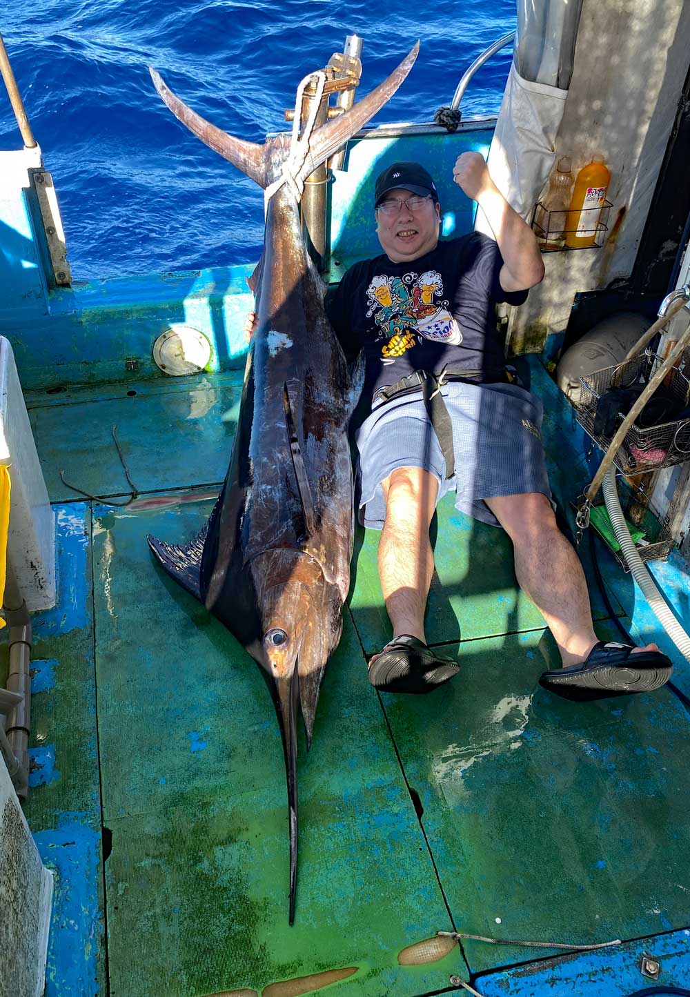 沖縄でカジキを釣り上げガッツポーズしているた新潟から来た男性