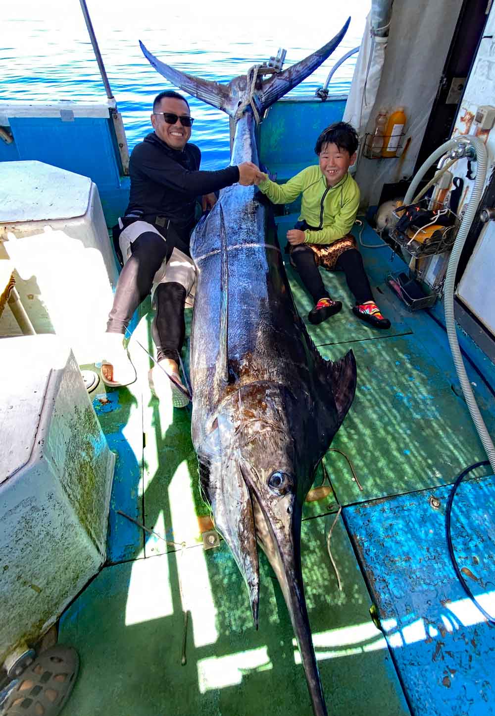 沖縄のトローリングで140kgのカジキ釣り上げ父と握手している8才の小学3年生