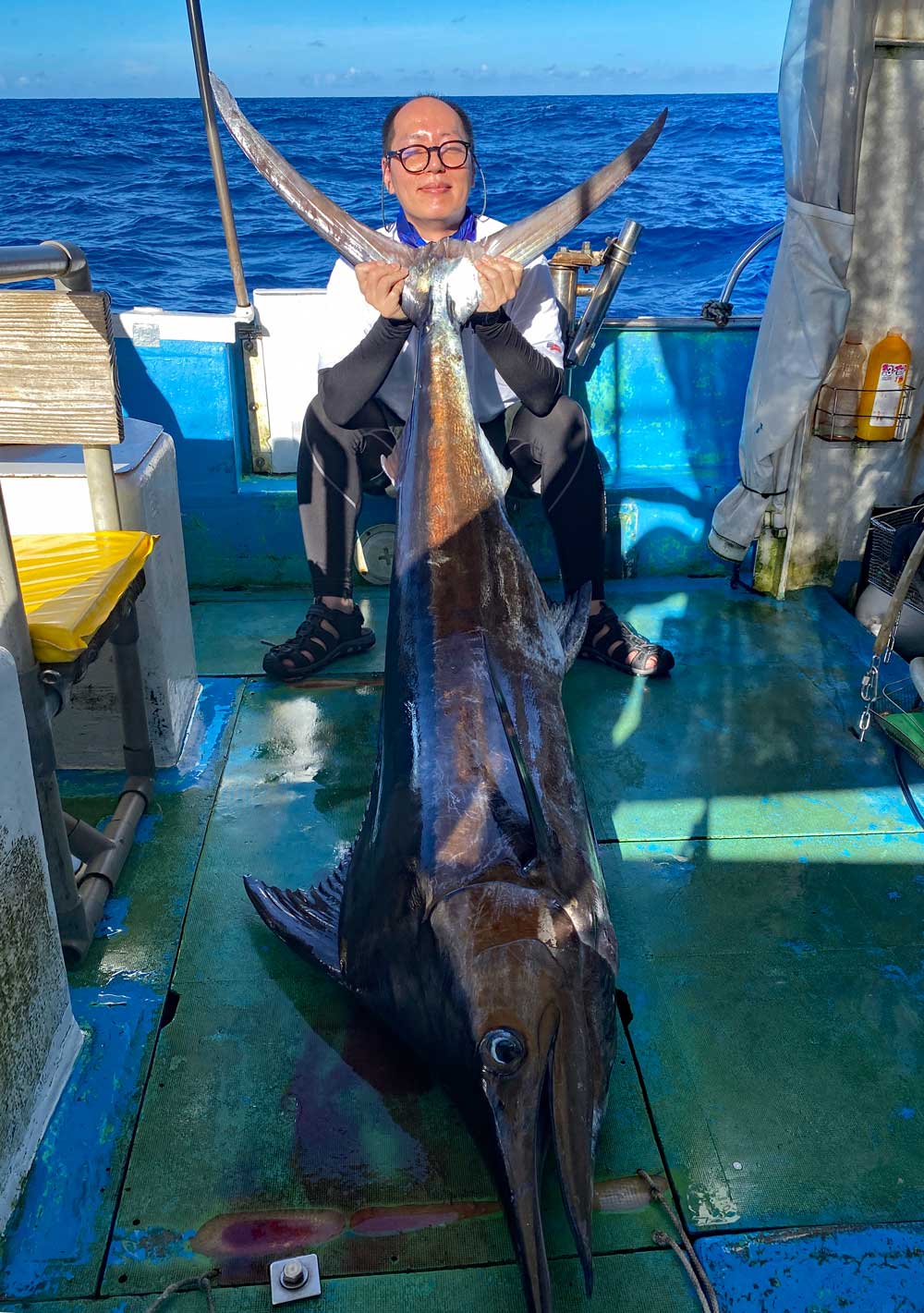 沖縄でカジキを釣り上げ尾を持ち上げている新潟の男性