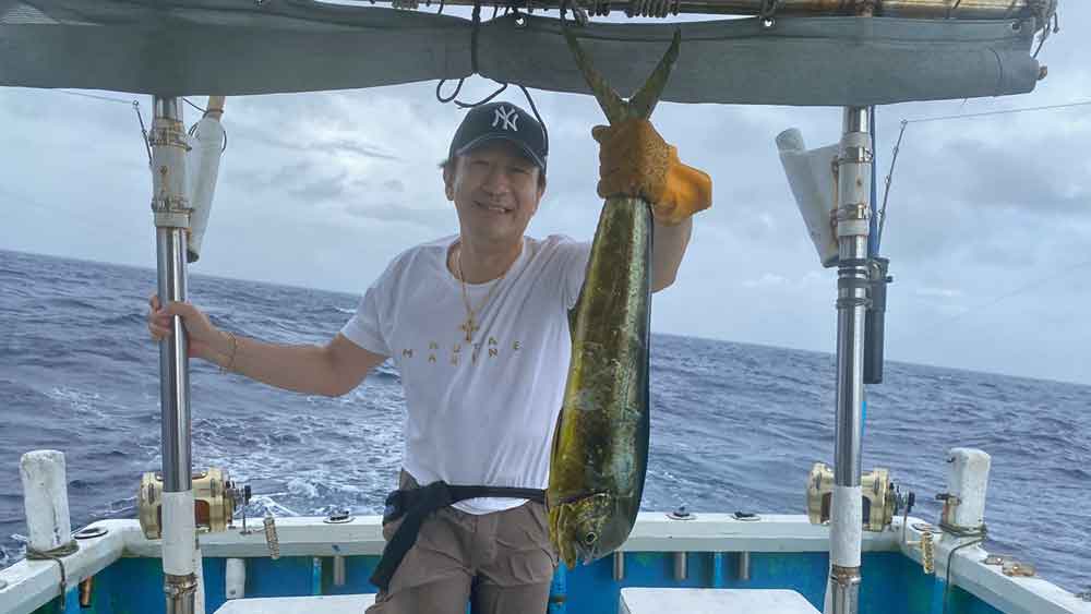 シイラの尾を左手で持ち上げている男性