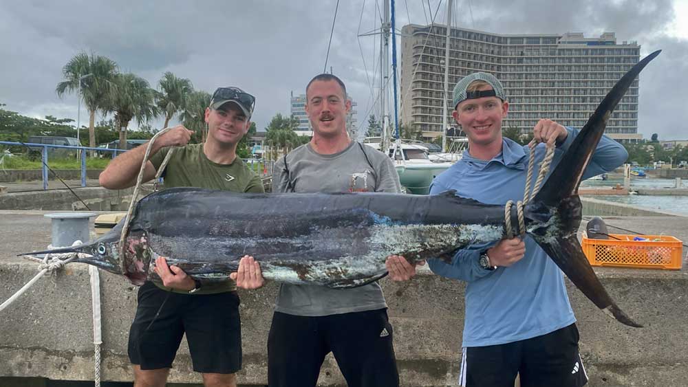 カジキを持ち上げている3人の男性