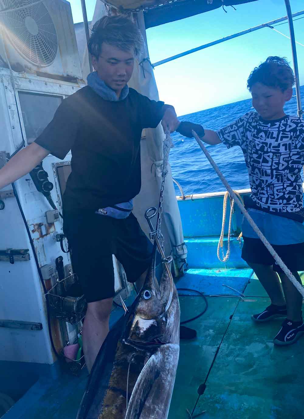 バショウカジキを船に引き上げている親子